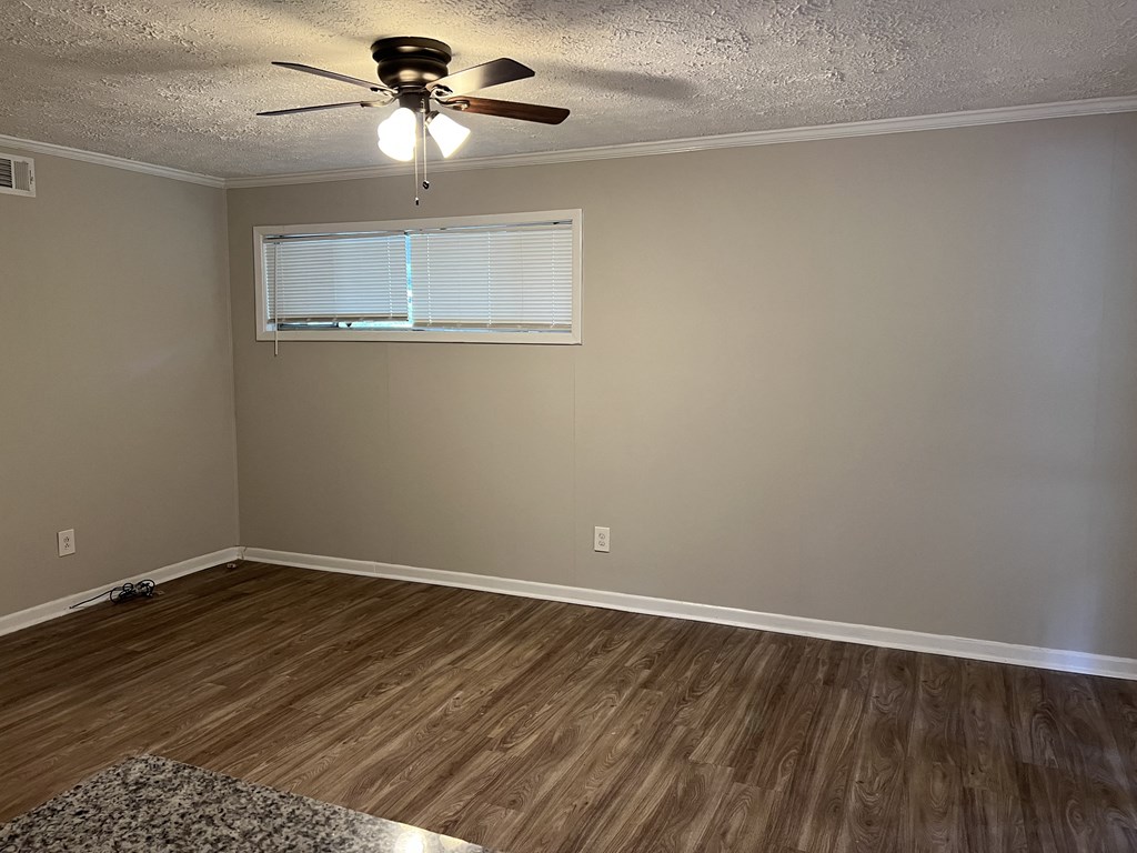an empty living room with a ceiling fan and a window