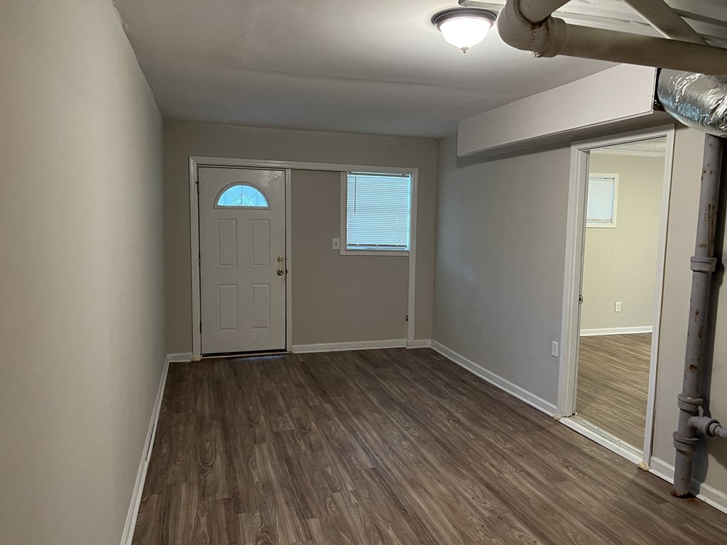 an empty living room with a white door and wood flooring