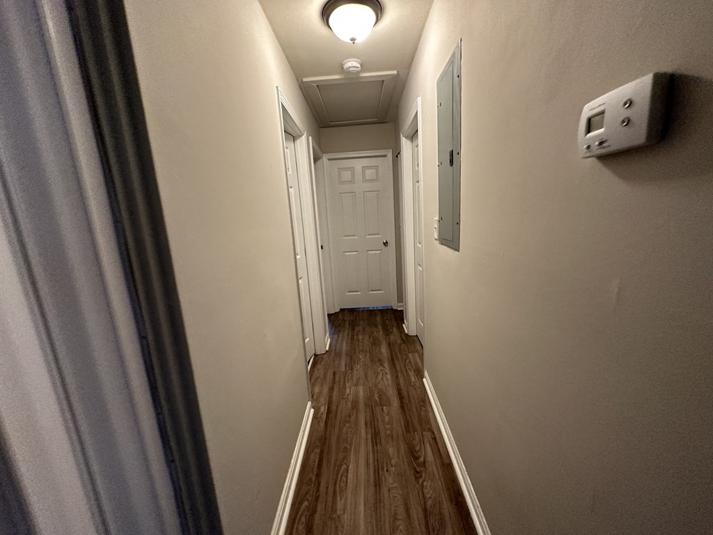 A long hallway with a white door at the end.