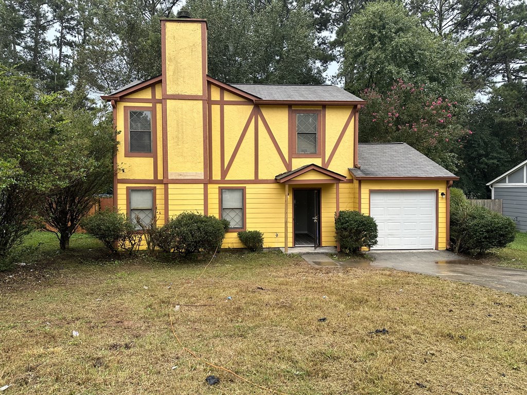 a yellow house with a garage in front of it
