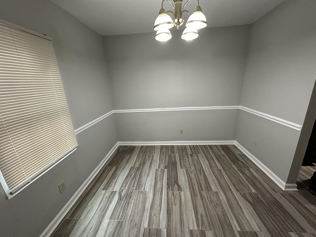 an empty room with wood flooring and a chandelier