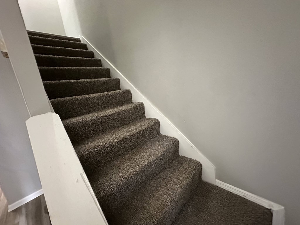 a carpeted staircase with a white railing and grey carpeted stairs with white walls