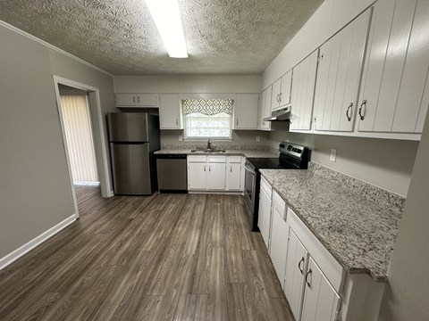 an empty kitchen with white cabinets and granite counter tops