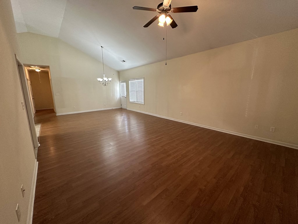 an empty living room with wood floors and a ceiling fan