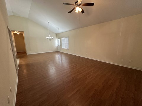 an empty living room with wood floors and a ceiling fan