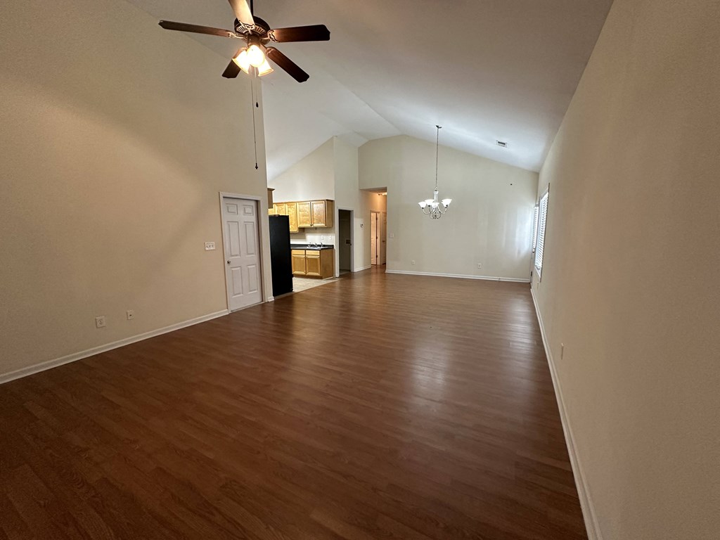 an empty living room with wood floors and a ceiling fan