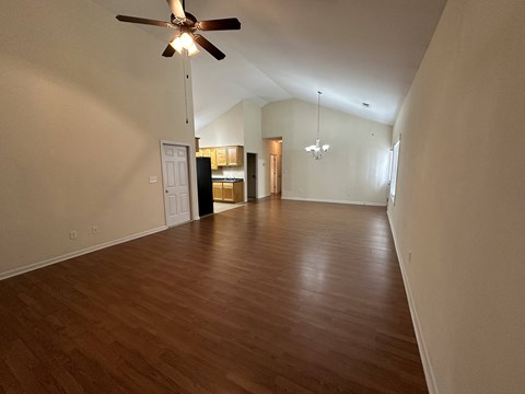 an empty living room with wood floors and a ceiling fan