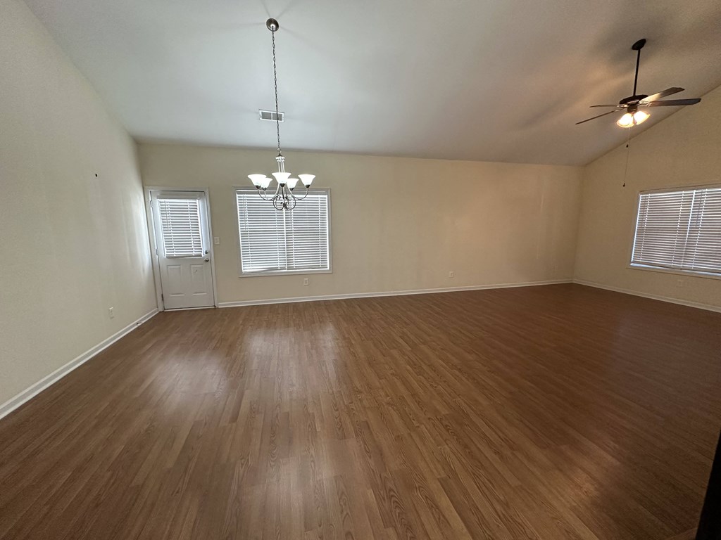 an empty living room with wood floors and a ceiling fan