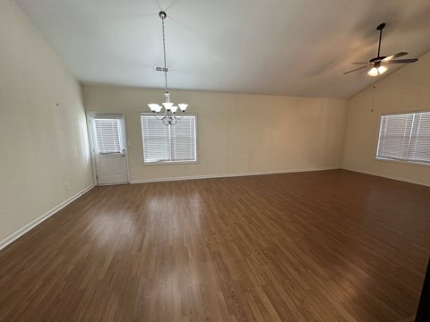 an empty living room with wood floors and a ceiling fan