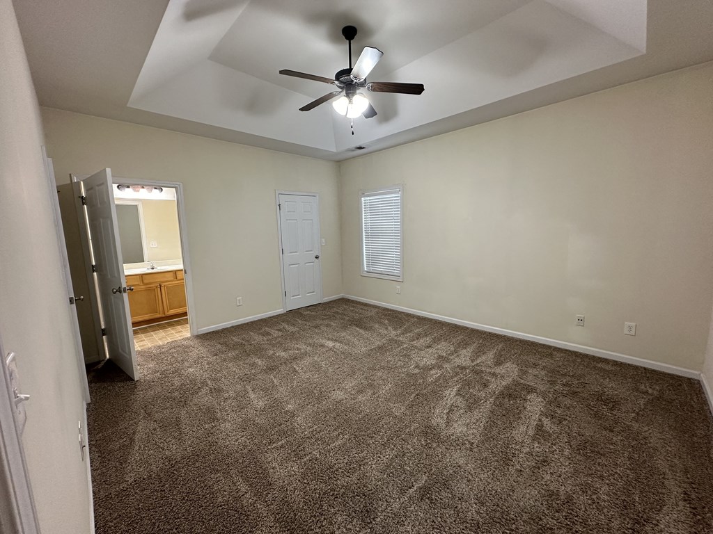 an empty living room with carpet and a ceiling fan
