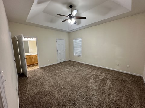 an empty living room with carpet and a ceiling fan