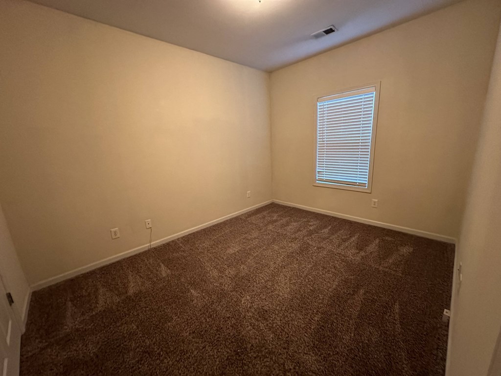 a empty room with brown carpet and a window