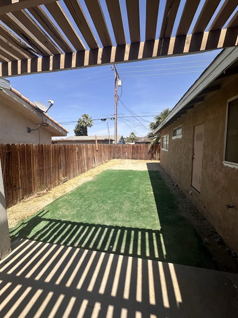 a backyard with a green lawn and a wooden fence