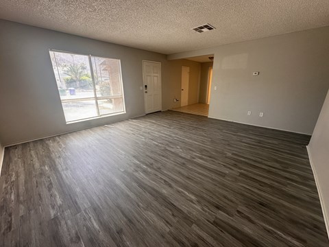 an empty living room with wooden floors and a window