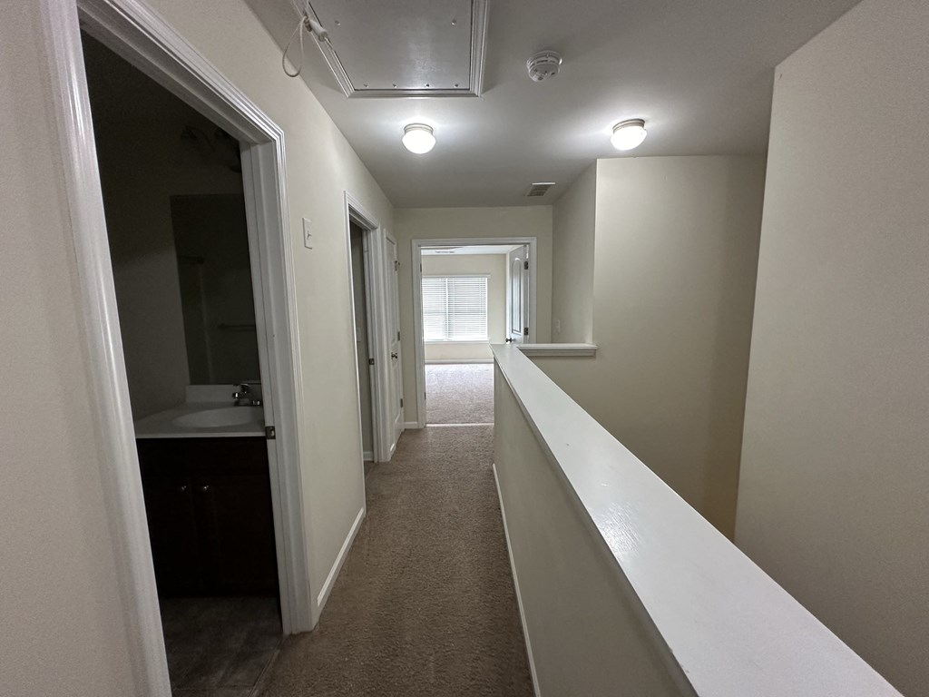 a long hallway with a sink and a mirror in a house