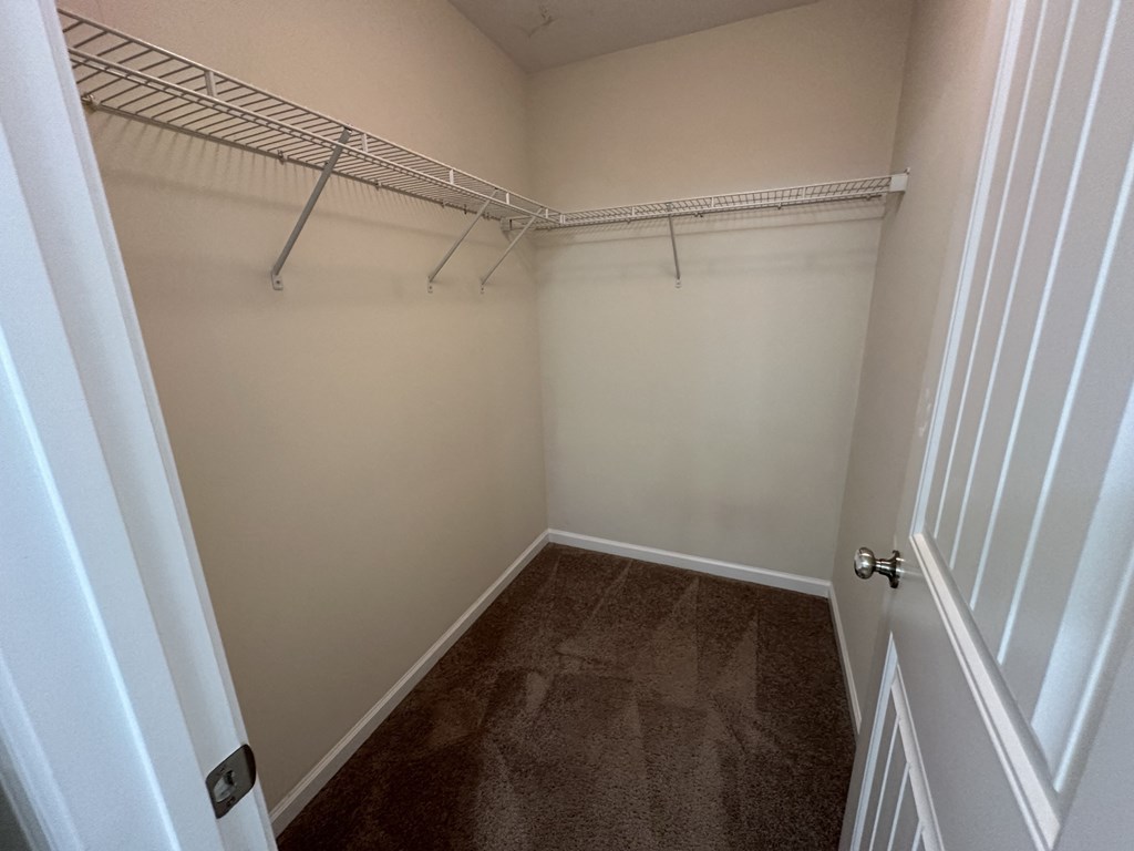 a walk in closet with a hanging rack on the wall