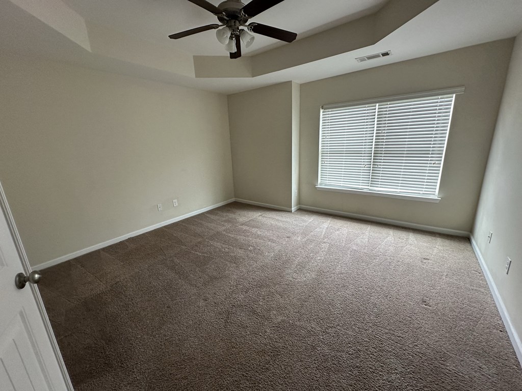an empty living room with a ceiling fan and a window
