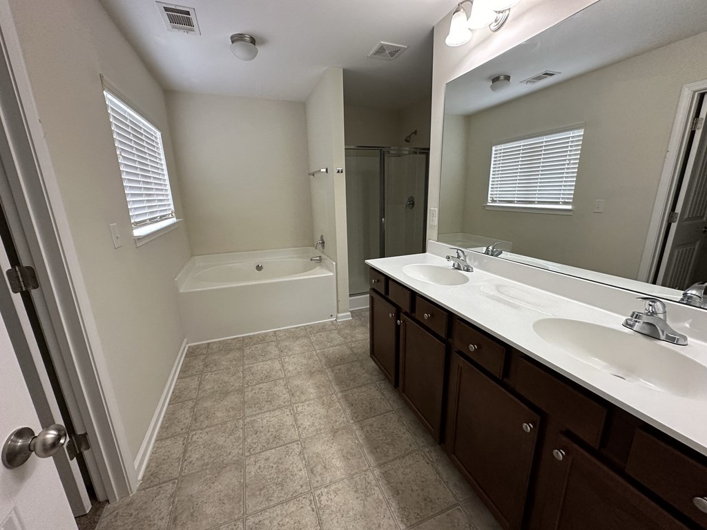 a bathroom with two sinks and a bath tub and a mirror