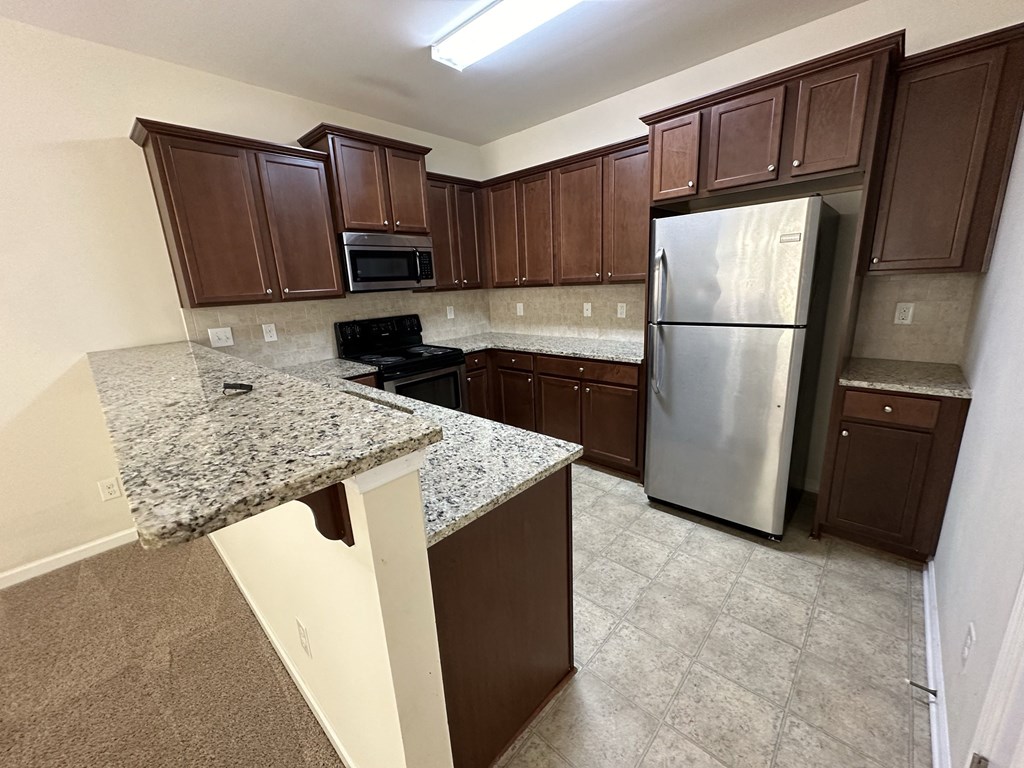 a kitchen with granite counter tops and a stainless steel refrigerator