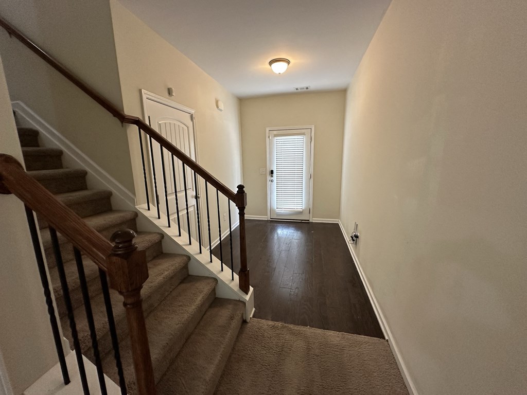 the landing of a staircase in a home with carpeted stairs and a white door
