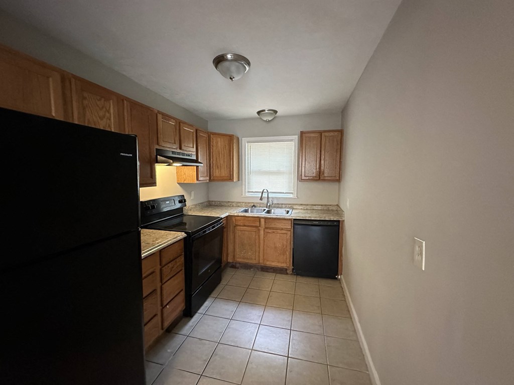 an empty kitchen with black appliances and wooden cabinets