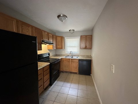 an empty kitchen with black appliances and wooden cabinets