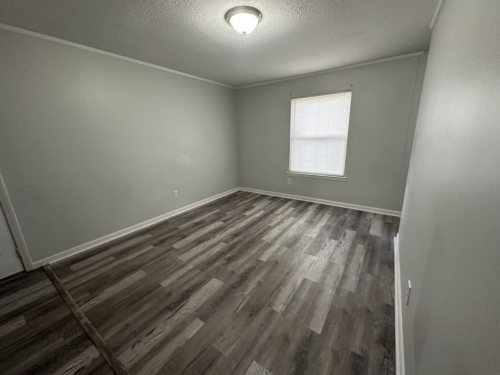 an empty living room with wood floors and a window