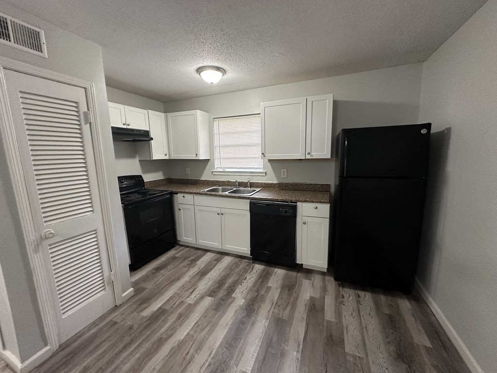 an empty kitchen with white cabinets and black appliances