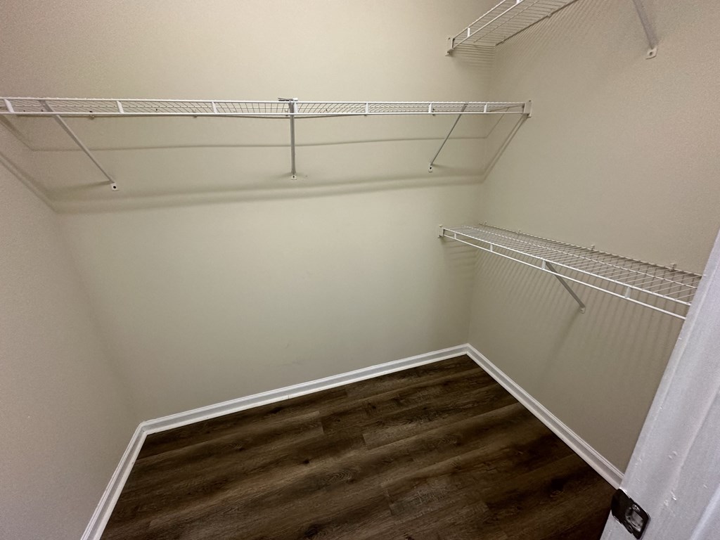 a walk in closet with shelves and a wood floor