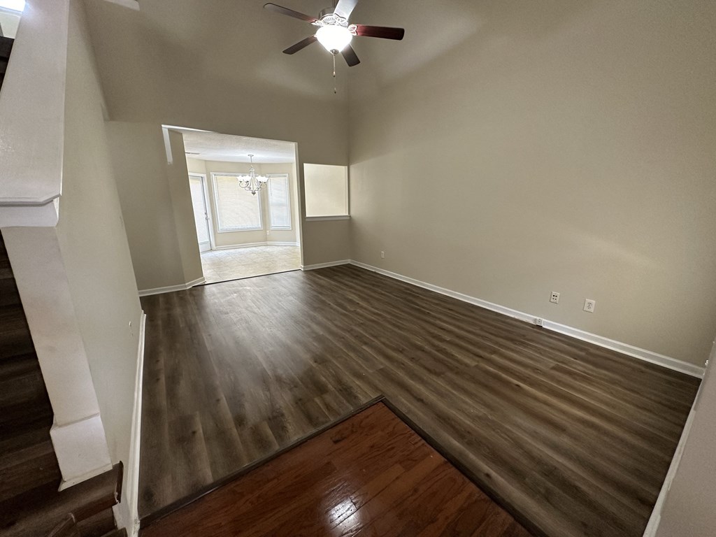 an empty living room with wooden floors and a ceiling fan