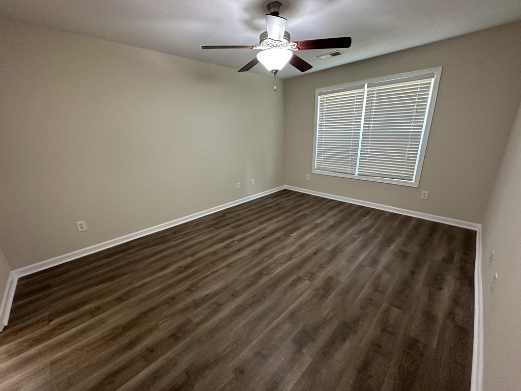 an empty living room with hardwood floors and a ceiling fan