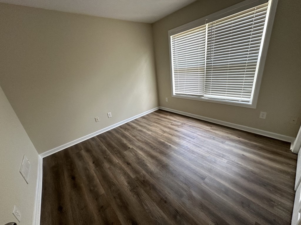 an empty living room with wooden floors and a window