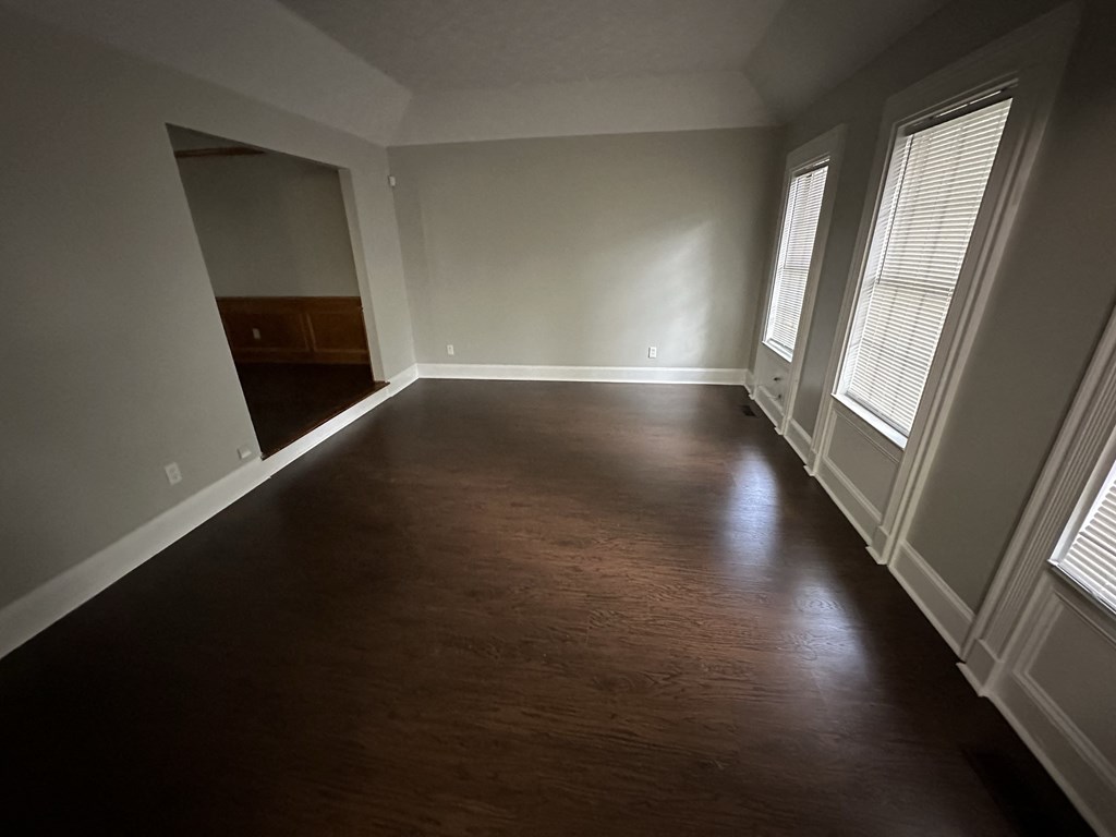 an empty living room with wood flooring and large windows
