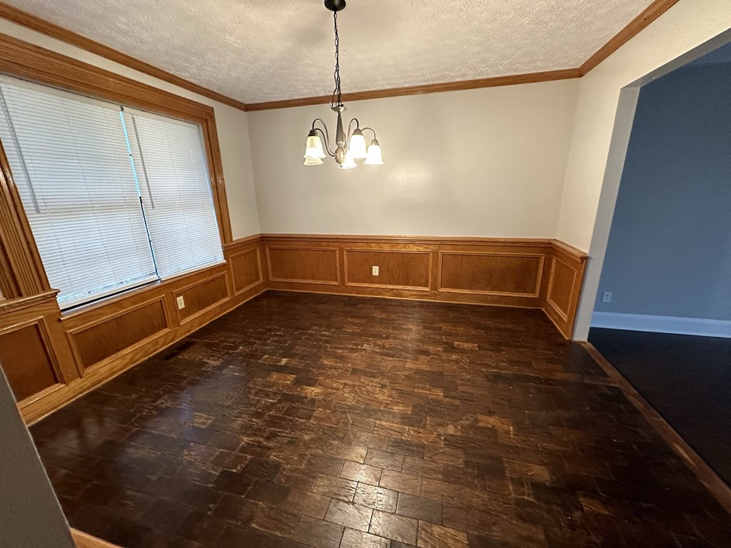 an empty dining room with wood floors and a chandelier
