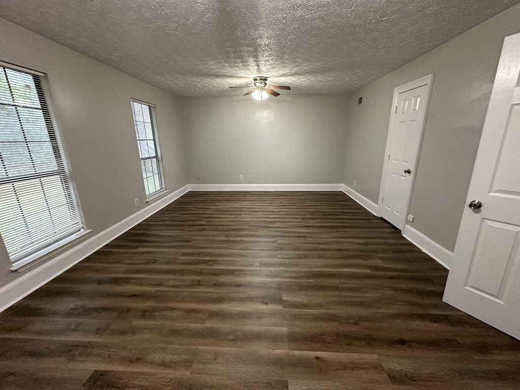 an empty living room with wood floors and a ceiling fan