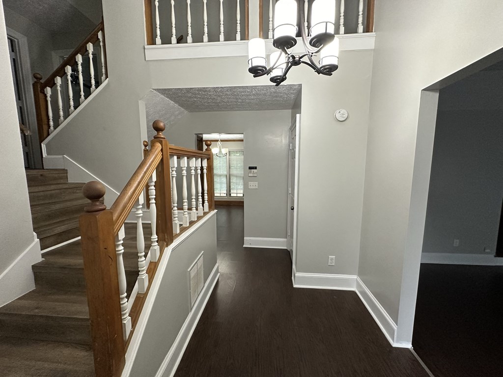 a look down the hallway of a house with stairs and a chandelier