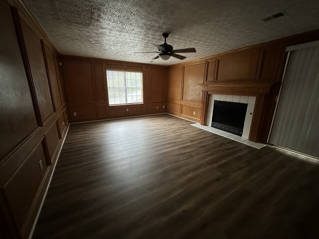 an empty living room with wooden floors and a ceiling fan