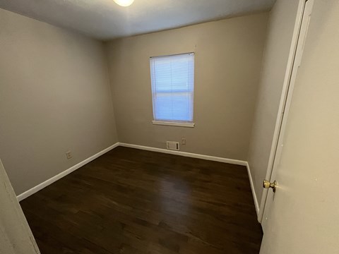 an empty room with wooden floors and a window