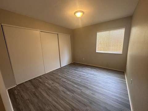 an empty bedroom with wood floors and a window