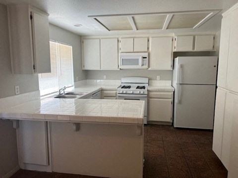 a white kitchen with a stove and a refrigerator