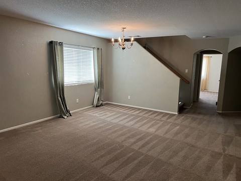 an empty living room with a staircase and a window