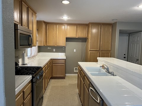 an empty kitchen with wooden cabinets and white counter tops