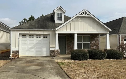 A house with a white garage door and a stone pillar.