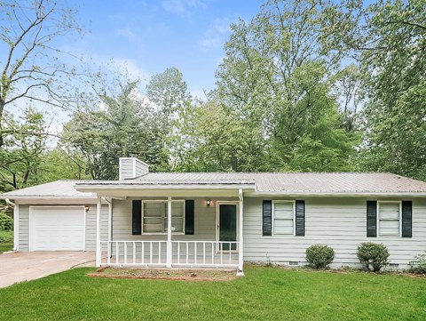 A white house with a porch and a chimney.
