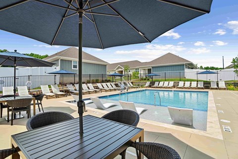 A poolside table with chairs and an umbrella over it. at Zora University, Charlotte, 28213