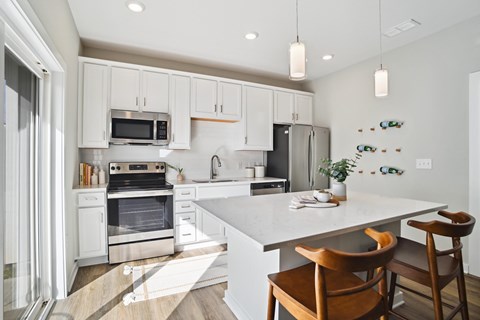 A kitchen with white cabinets and a white island with a wooden chair.