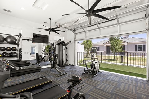 a gym with weights and cardio equipment and a large window at Zora Encanto, Phoenix, Arizona