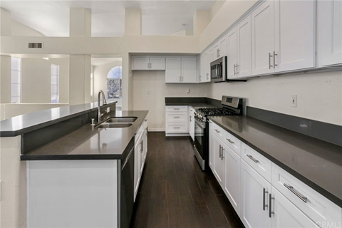 a large kitchen with white cabinets and black counter tops