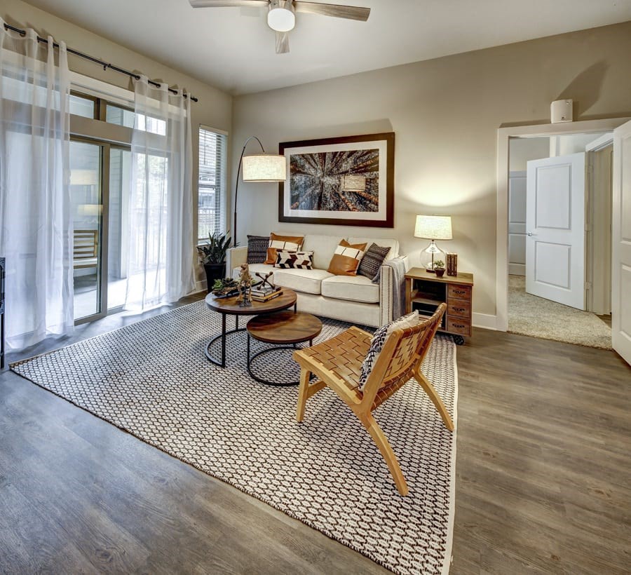 A living room with a couch, coffee table, and a painting on the wall at Arise Riverside Apartments, Austin, TX
