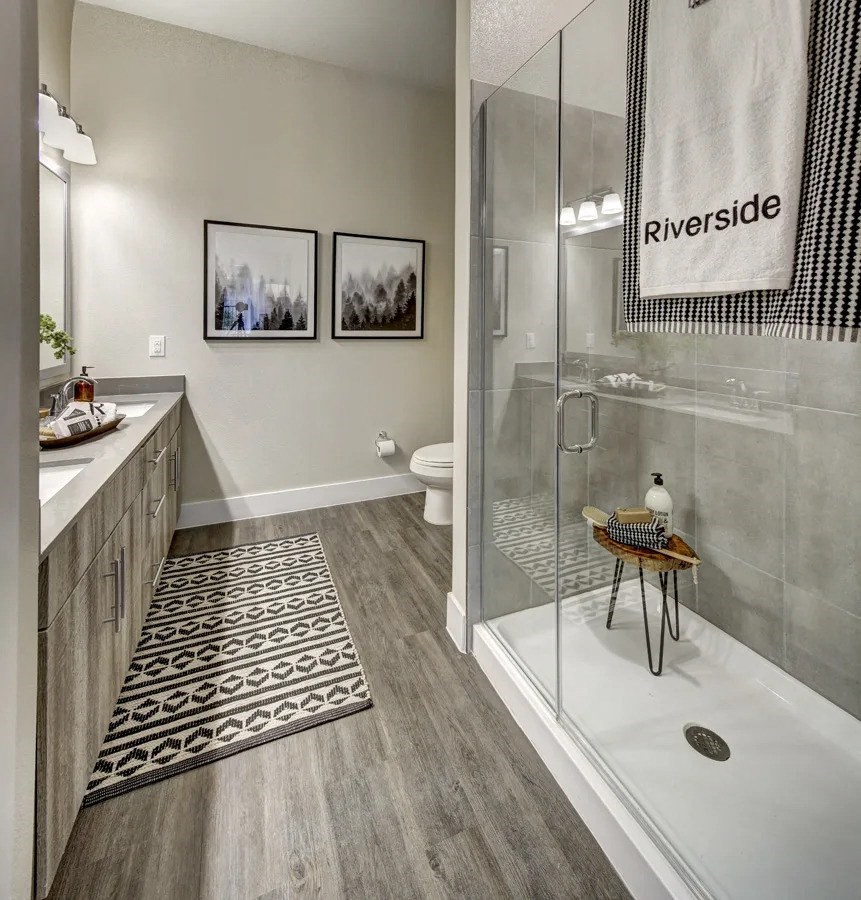 A bathroom with a glass shower stall and a towel hanging on the glass door at Arise Riverside Apartments, Austin, 78741